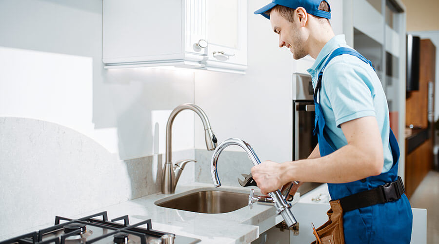 plumber-in-uniform-changes-faucet-in-the-kitchen-8YY2ZB5.jpg